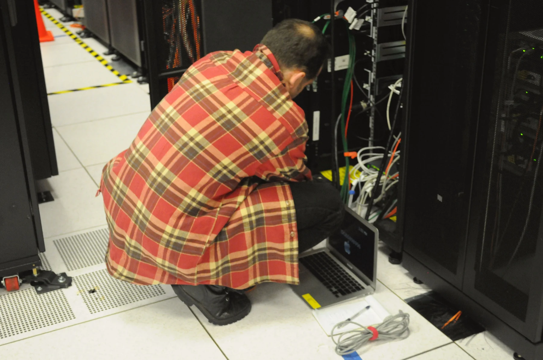Technik pracujący przy szafie serwerowej w centrum obliczeniowym